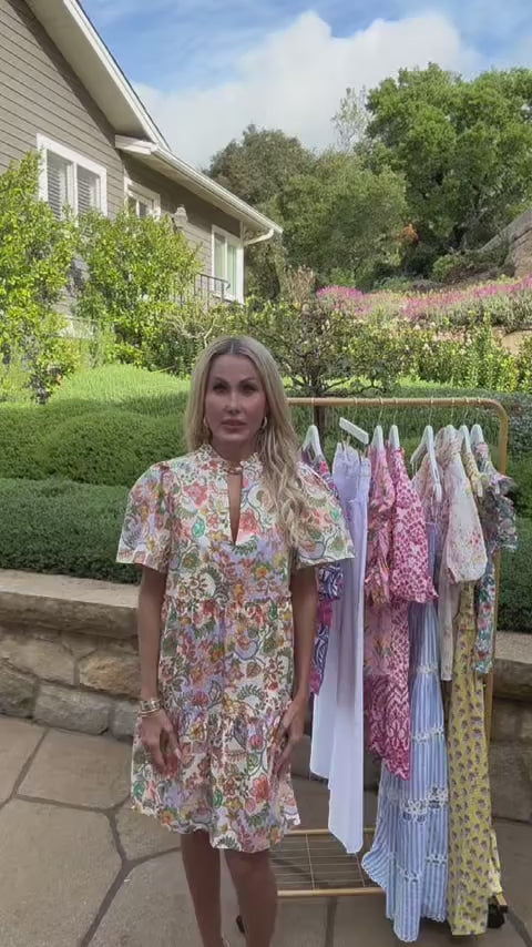Woman wearing multi floral short dress outside in front of clothing rack