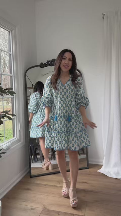 Woman wearing blue floral camilla dress with a mirror in background
