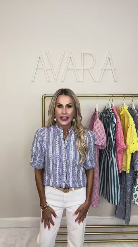 woman wearing a blue stripe gia top with a rack of clothing in the background