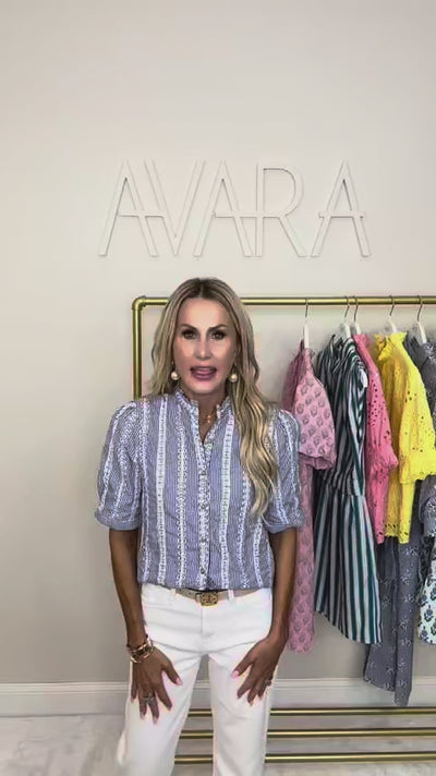 woman wearing a blue stripe gia top with a rack of clothing in the background