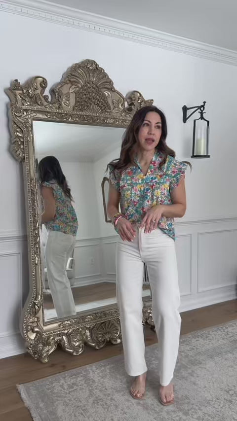woman wearing Floral Audrey Multi flutter sleeve top with white jeans with mirror in background