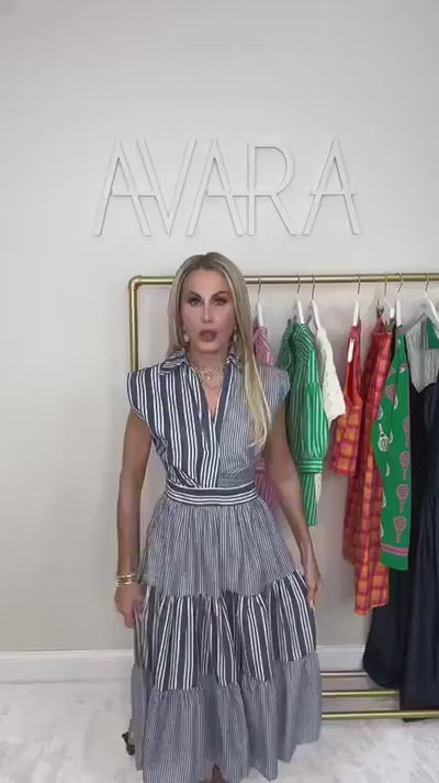 Model wearing navy striped midi dress in front of white wall and clothing rack